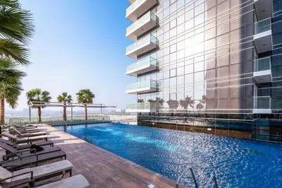 an exterior view of a hotel with a swimming pool at Chic Studio in Damac Hills Carson B, Dubailand by Deluxe Holiday Homes in Dubai