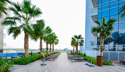 a row of chairs and palm trees on the side of a building at Chic Studio in Damac Hills Carson B, Dubailand by Deluxe Holiday Homes in Dubai