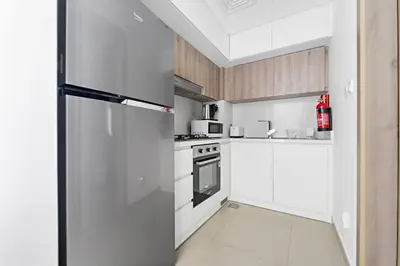 a kitchen with white cabinets and a refrigerator at Modern Studio Near To Park in Dubai