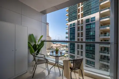 a balcony with a table and chairs and a large window at Modern studio near the beach in Dubai