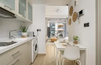 a white kitchen with a sink and a table at Modern studio near the beach in Dubai