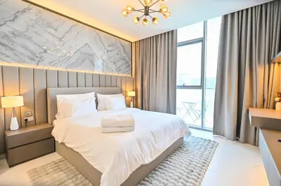 a bedroom with a bed and a large window at Spacious 1BR Burj Khalifa Views in District One Meydan in Dubai