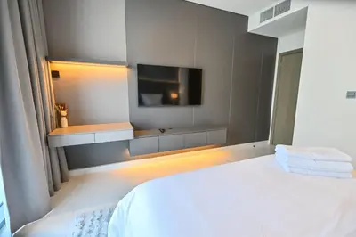 a bedroom with a white bed and a flat screen tv at Spacious 1BR Burj Khalifa Views in District One Meydan in Dubai