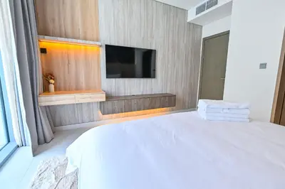 a bedroom with a white bed and a tv at 1BR Close to Crystal Lagoon in District One Meydan in Dubai