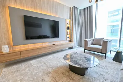 a living room with a large flat screen tv on a wall at 1BR Close to Crystal Lagoon in District One Meydan in Dubai