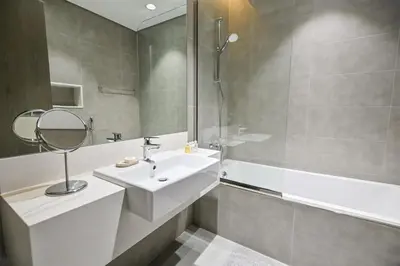 a bathroom with a sink and a mirror and a tub at Direct Access to Crystal Lagoon 1br unit in District One Meydan in Dubai