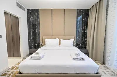 a bedroom with a large white bed with two towels at Direct Access to Crystal Lagoon 1br unit in District One Meydan in Dubai