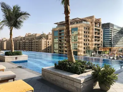 a large swimming pool with palm trees and buildings at Luxury 1-BR with Stunning Views in Palm Tower by Luxe Shortlet in Dubai