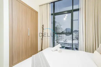 a bedroom with a white bed and a large window at Relaxing 1BR Apartment with Built-in Wardrobe & Community View in Azizi Riviera 4, Al Merkadh by Deluxe Holiday Homes in Dubai