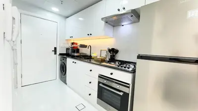 a kitchen with white cabinets and a stove top oven at Dubai Marina - Cozy Studio Apartment in Dubai