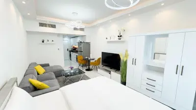 a white living room with a couch and a tv at Dubai Marina - Cozy Studio Apartment in Dubai