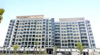 a tall building with palm trees in front of it at Lovely Studio Apartment at Azizi Riviera 46 in Al Merkadh by Deluxe Holiday Homes in Dubai