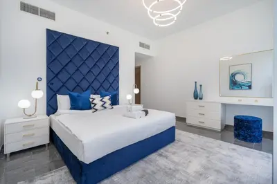 a bedroom with a large bed with a blue headboard at AirDXB - Exceptional 3bedroom with the incredible view in Dubai Marina in Dubai