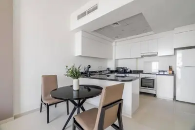 a kitchen with a table and chairs and a kitchen with white cabinets at Exquisite 1Bedroom With City Views in Dubai