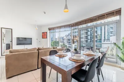 a living room with a table and a couch at Elegant 2BR in Park Island Bonaire, Dubai Marina by Deluxe Holiday Homes in Dubai