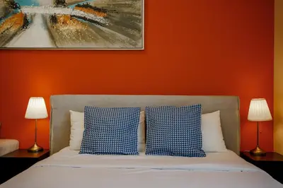 a bedroom with an orange wall and a bed with blue and white pillows at Cozy studio in Business Bay Dubai in Dubai