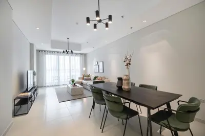 a dining room and living room with a table and chairs at 2BR API 1000 Community View Jumeirah in Dubai