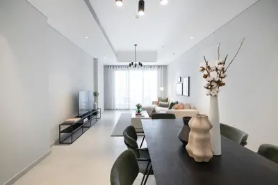 a dining room and living room with a table and chairs at 2BR API 1000 Community View Jumeirah in Dubai