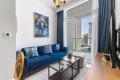 a living room with a blue couch and a window at Exclusive Burj Khalifa View - Modern 1 BR in Dubai