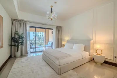 a white bedroom with a bed and a balcony at Apartment with Palm Jumeirah view I Golden Mile in Dubai