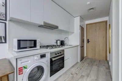 a kitchen with a washing machine and a microwave at Knokey Ahad Residence in Dubai