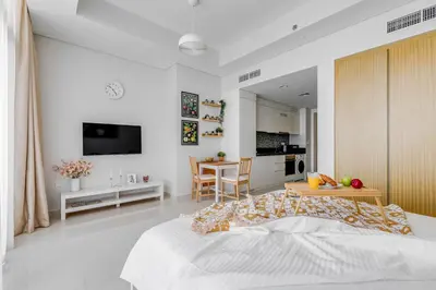 a bedroom with a bed and a table and a kitchen at Knokey Aykon City in Dubai