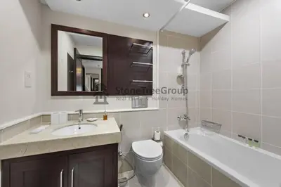 a bathroom with a sink and a toilet and a mirror at Stylish 1 Br In Unique Location in Dubai
