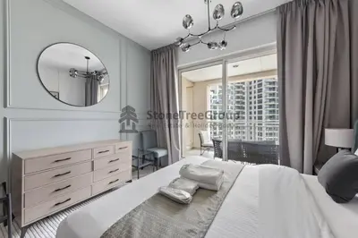 a bedroom with a large white bed and a mirror at Stylish 1 Br In Unique Location in Dubai