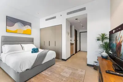 a bedroom with a large bed and a television at Waves - Fully Equipped Studio for a Perfect Stay in Dubai in Dubai
