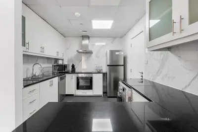 a large white kitchen with white cabinets and appliances at Sea View apt in JBR - 2 BR in front of the beach in Dubai