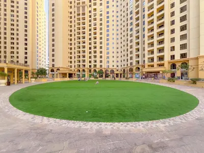 a large grassy area in front of tall buildings at Sea View apt in JBR - 2 BR in front of the beach in Dubai