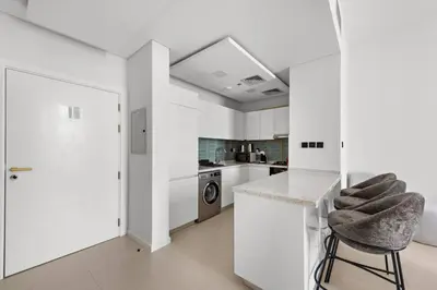 a kitchen with white walls and a counter and a stool at Unique 1 BHK Near To Metro in Dubai