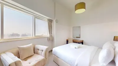a living room with a couch and a bed and a window at The Bridge - Tranquil Two Bedroom in Sports City in Dubai