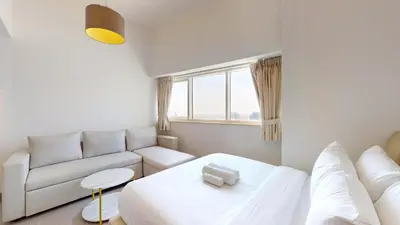 a white living room with a couch and a bed at The Bridge - Tranquil Two Bedroom in Sports City in Dubai