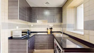 a kitchen with wooden cabinets and a sink at The Bridge - Tranquil Two Bedroom in Sports City in Dubai