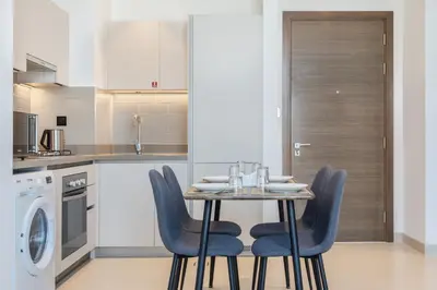 a kitchen with a table and blue chairs in a kitchen at STAY BY LATINEM Luxury 1BR Holiday Home CV B1311 near Burj Khalifa in Dubai