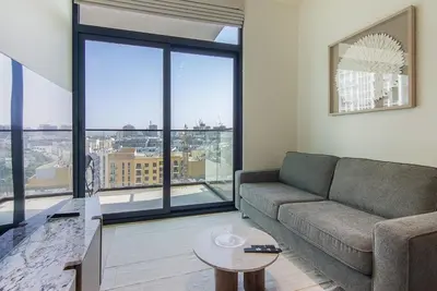 a living room with a couch and large windows at Binghatti Emerald, JVC- Charming 1-BR Apartment in Dubai