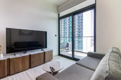 a living room with a couch and a large window at Binghatti Emerald, JVC- Charming 1-BR Apartment in Dubai
