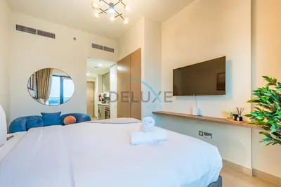 a bedroom with a large white bed and a tv at Chic Studio in Azizi Riviera 44, Al Merkadh by Deluxe Holiday Homes in Dubai