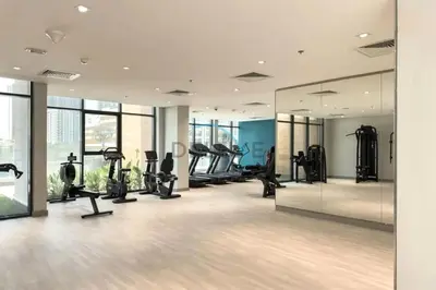 a gym with treadmills and ellipticals and mirrors at Chic Studio in Azizi Riviera 44, Al Merkadh by Deluxe Holiday Homes in Dubai
