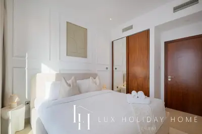 a white bedroom with a large white bed with white pillows at LUX The Marina Gate Sea View Suite in Dubai