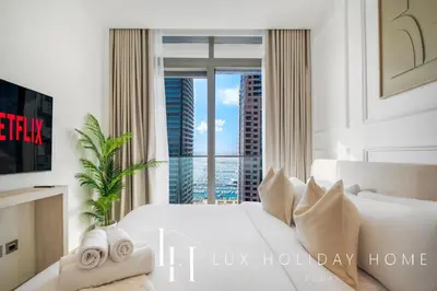 a bedroom with a white bed and a large window at LUX The Marina Gate Sea View Suite in Dubai