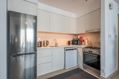 a kitchen with white cabinets and a stainless steel refrigerator at Luxuswohnung in Creek Harbour in Dubai