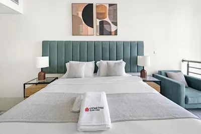 a bedroom with a large bed with a green headboard at Large 1 BR Duplex With Lake View in Dubai
