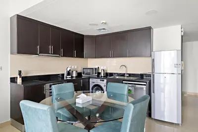 a kitchen with a glass table and blue chairs at Large 1 BR Duplex With Lake View in Dubai