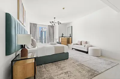 a white bedroom with a bed and a couch at Large 1 BR Duplex With Lake View in Dubai