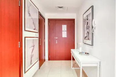 a hallway with a red door and a white table at Elite 1 BR in JBR with Marina Views in Dubai