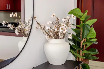 a white vase sitting on a table next to a plant at Beautiful and bright 1 bedroom apartment! Sofia ! in Dubai