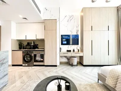 a living room with white cabinets and a kitchen at Indulge in a Regal Retreat at JVC in Dubai