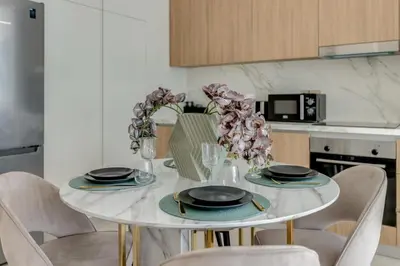 a dining room table with chairs and a white table with flowers at Beach Vista - Private Beach & Palm Jumeirah Views in Dubai